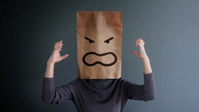 A man in anger wearing paper bag with angry face drawn