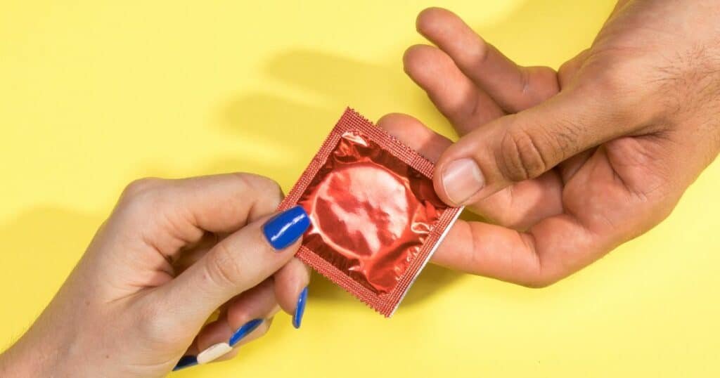 a man and a woman's hand shot holding a condom.