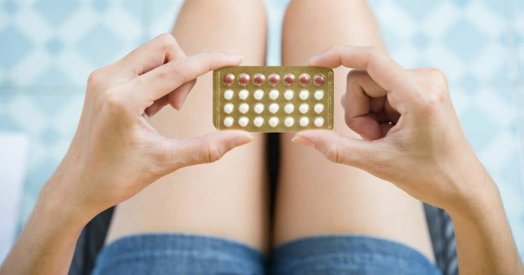 a woman holding contraceptive pills
